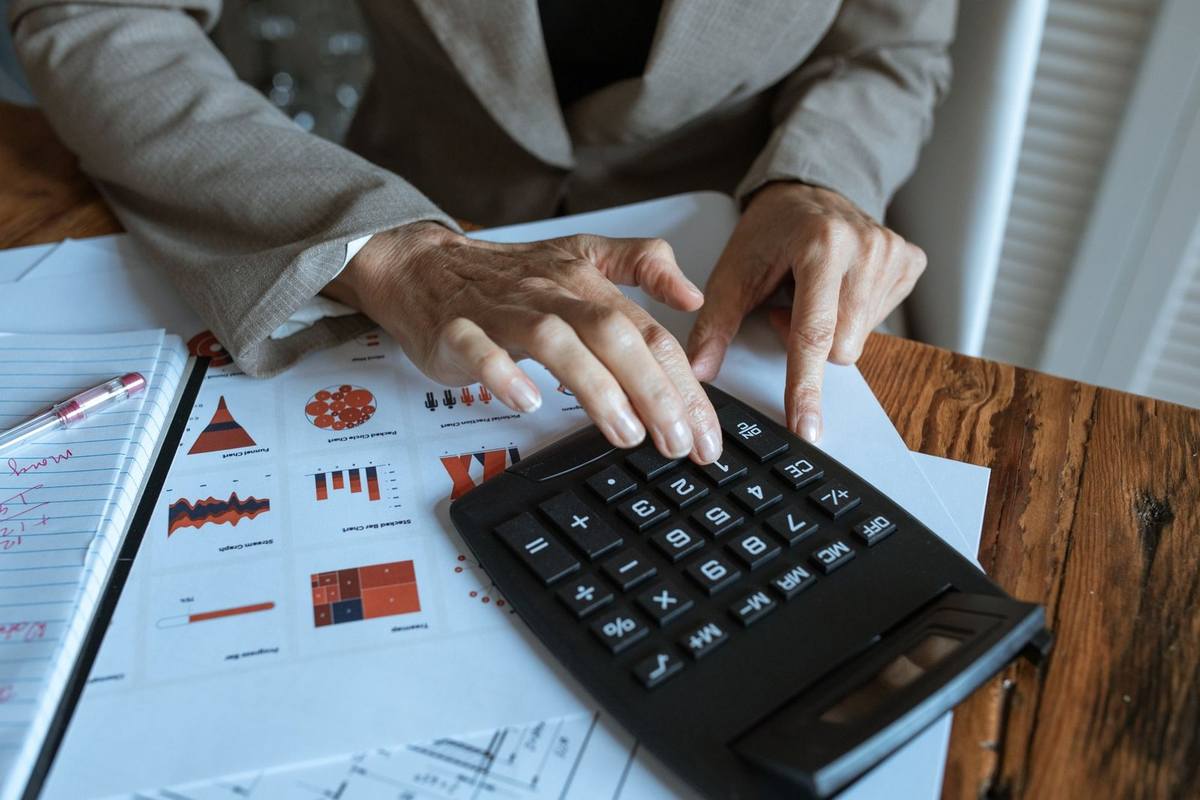 Une personne utilise un calculateur sur une table avec des documents et un stylo