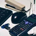 Clavier, souris, calculatrice, agrafeuse, clé USB, papiers sur un bureau