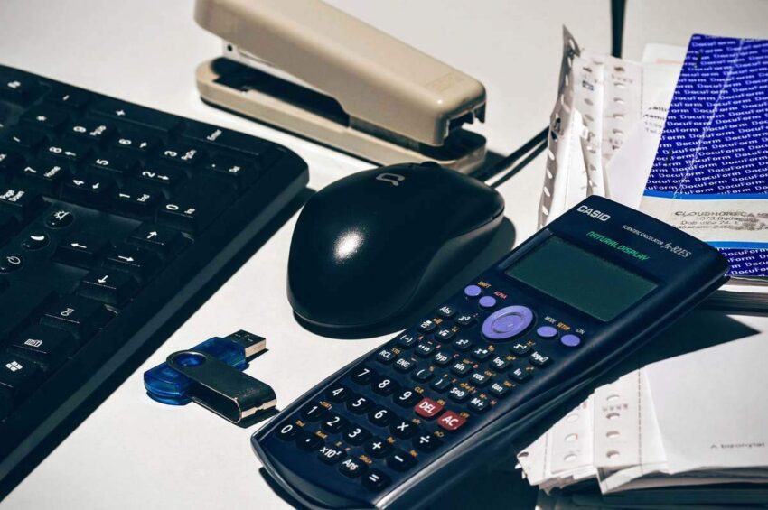 Clavier, souris, calculatrice, agrafeuse, clé USB, papiers sur un bureau
