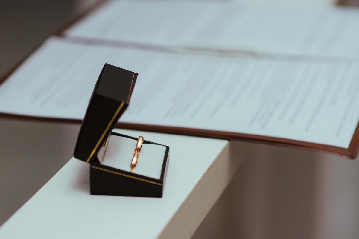 Anneau en or dans une boîte ouverte sur une table, documents flous derrière
