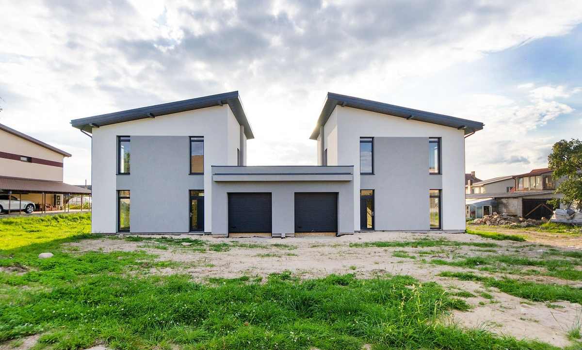 Maison blanche à deux étages avec garage, quartier en construction, ciel nuageux