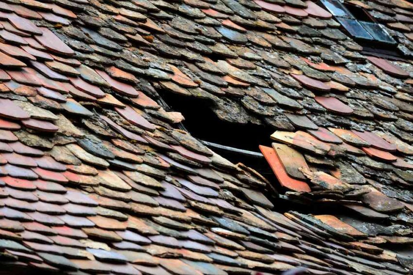 Panneau de toit endommagé avec tuiles déplacées et trou noir